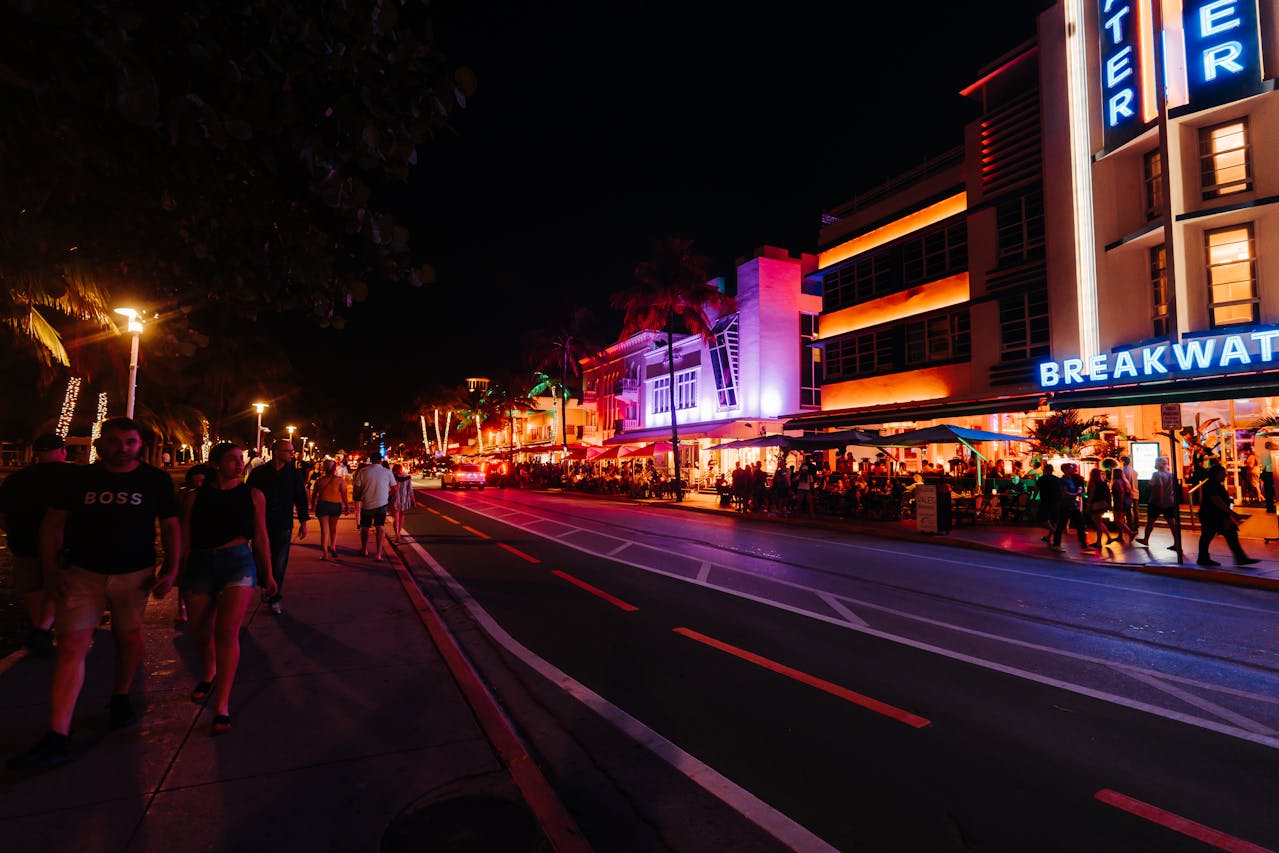 A lively scene of Ocean Drive lit up at night.