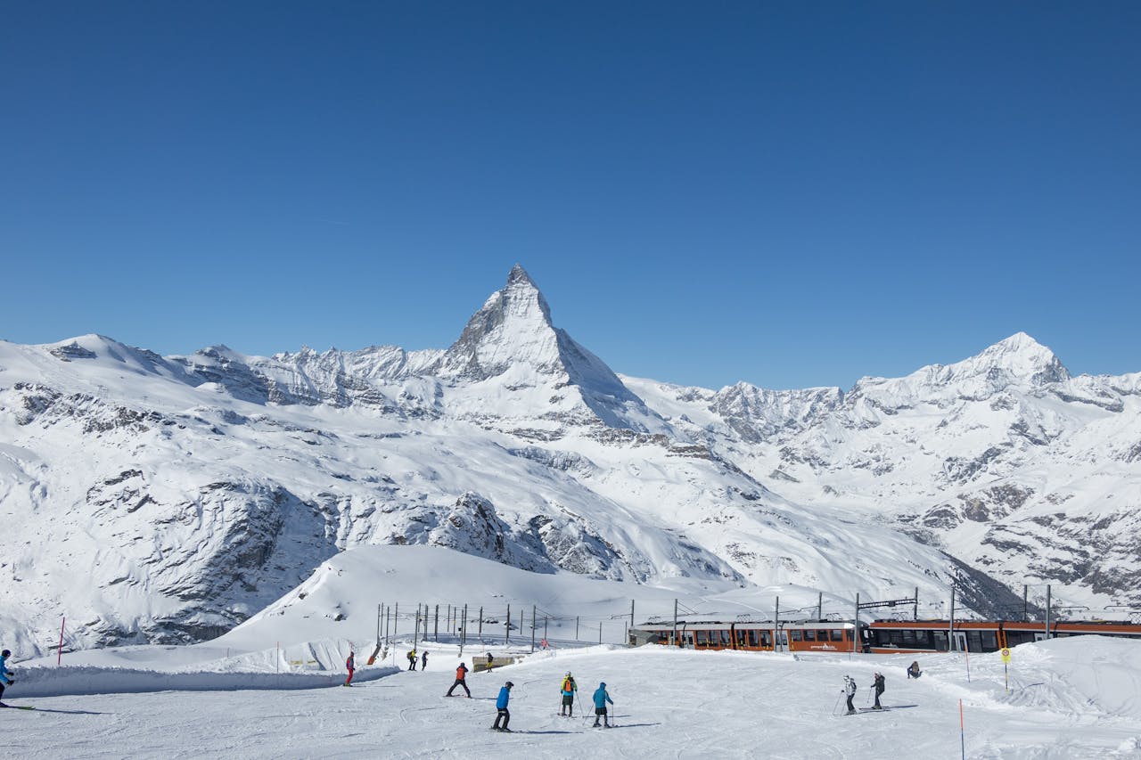 A skiers on snowy slopes with the Alps in the background